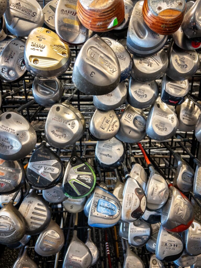 A collection of various used golf club heads in a store display.
